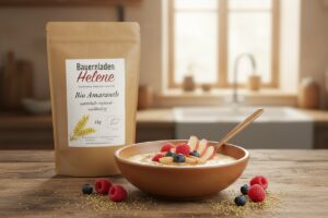 Schale Amaranth-Porridge mit Himbeeren, Heidelbeeren und Apfelspalten, dahinter Bio Amaranth von Bauernladen Helene